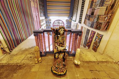 Merida, Yucatan, Meksika, İskelet heykeli renkli duvar halıları olan bir odada bir çıkıntının üzerinde duruyor. Odanın eşsiz ve eklektik bir stili var, farklı renk ve desenlerin karışımı. İskelet heykel gizem ve entrika katıyor 