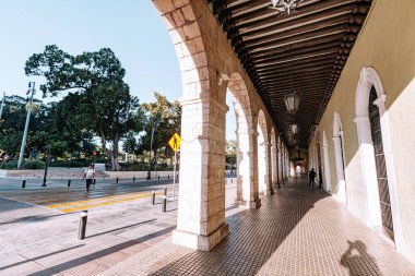 Merida, Yucatan, Meksika, yan tarafında sarı bir işaret olan uzun, dar bir patika. Geçit kemerli sütunlarla kaplı ve üzerinde yürüyen birkaç kişi var.