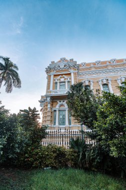 Merida, Yucatan, Meksika, önünde bir sürü pencere ve çit olan büyük bir bina. Bina sarı ve beyaz.