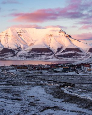 Longyerbeyen, Svalbard, uzak bir kasabası olan dağ sırası. Gökyüzü pembe ve güneş batıyor.