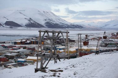 Longyerbeyen, Svalbard, arka planda kayak asansörü olan küçük bir kasaba. Kasaba karla kaplı ve gökyüzü bulutlu.