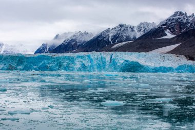 Svalbard seyahati. Üstünde mavi bir buz tabakası olan büyük bir su kütlesi. Su dondu ve buz tabakası eriyor.