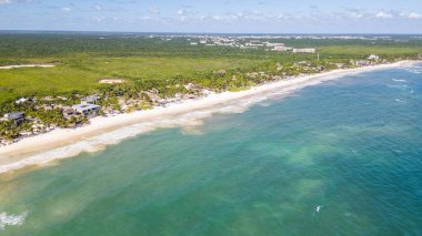 Tulum Sahili, Quintana Roo, Meksika. Temiz mavi okyanuslu güzel bir sahil ve arka planda yeşil bir orman. Kumsal, günün tadını çıkaran insanlarla dolu.
