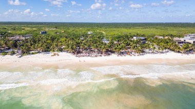 Tulum Sahili, Quintana Roo, Meksika, Palmiye ağaçları ve açık mavi gökyüzü olan plaj. Sahil, günün tadını çıkaran insanlarla dolu.