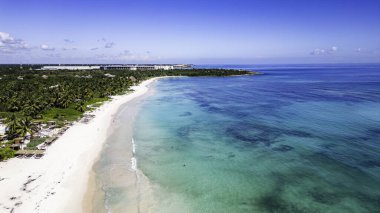 Arkasında açık mavi bir okyanus olan güzel bir sahil. Kumsal boş ve su sakin.