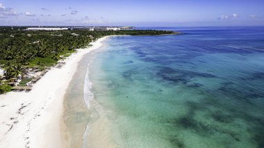 Arkasında açık mavi bir okyanus olan güzel bir sahil. Kumsal boş ve su sakin.