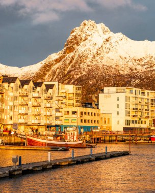 Svolvear, Lofoten Adası, Norveç Arkasında büyük bir dağ. Binalar uzun ve beyaz. Su sakin ve gökyüzü bulutlu.
