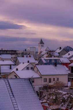 Svolver Norveç Lofoten Adaları 'nda arka planda bir kilise olan Karlı bir kasaba. Gökyüzü mavi ve mor karışımı.