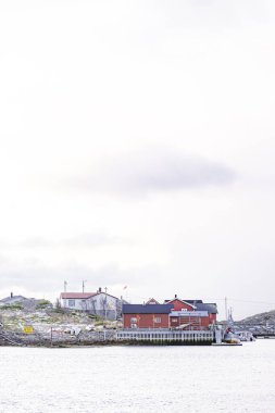 Kırmızı evi ve beyaz evi olan küçük bir kasaba. Evler su kenarında bir rıhtımda.