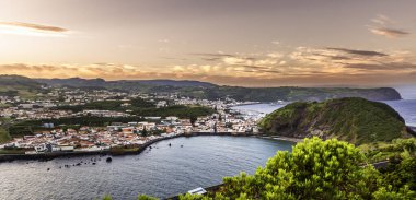 Faial, Azores Adaları, Portekiz Körfezi ve plajı olan güzel bir şehir manzarası. Gökyüzü turuncu ve pembe renklerin karışımıdır.