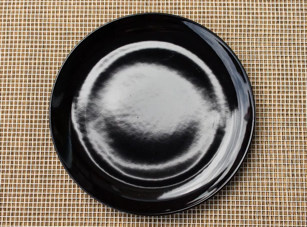 Black empty plate  on netting background — Stock Photo, Image