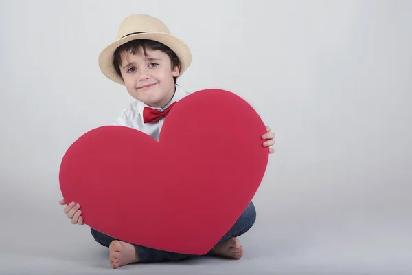 Niño sonriente con un corazón rojo — Foto de Stock