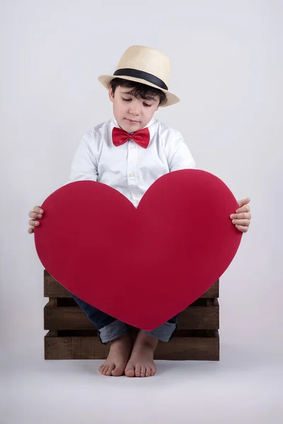 Niño reflexivo con un corazón rojo — Foto de Stock