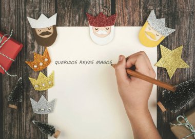Child hands writing letter to the three kings of orient over wooden background.Christmas concept background. clipart