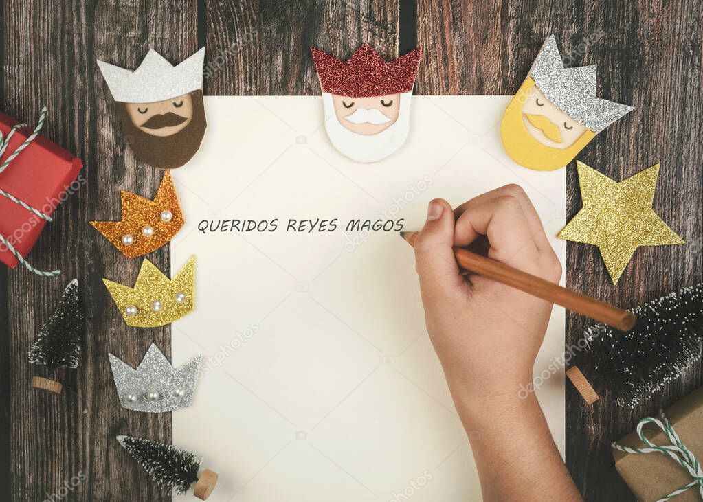 Child hands writing letter to the three kings of orient over wooden background.Christmas concept background.