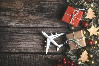 Yılbaşı gezisi konsepti. Ahşap arka planda noel süslemesi olan uçak.