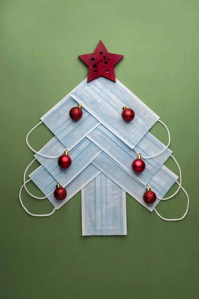 クリスマスの概念の背景 緑の背景にクリスマスツリーの形で保護外科用マスク — ストック写真