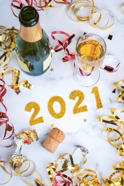 happy New Year 2021. New Years Eve celebration concept background.Champagne bottle with glass and confetti on marble table.Selective focus