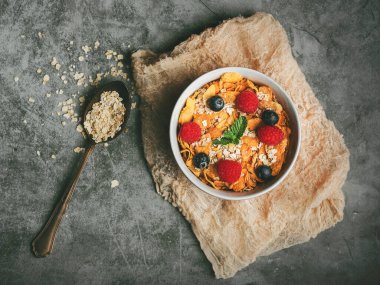 Sağlıklı kahvaltı. Mısır gevreği, ahududu ve yaban mersinli kase ve grunge arkaplanda bir kaşık.