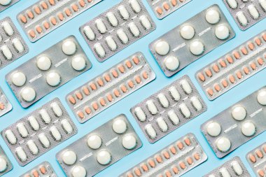 Geometrik desen, beyaz tabletlerle ve mavi arka planda ağrı kesicilerle yapılmış. Tıp kavramı