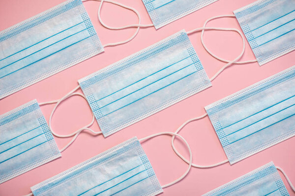 Geometric pattern made with protective surgical masks on pink background.Covid 19 concept