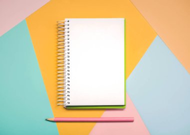 Sarmal not defteri ve renkli arkaplanda kopyalama alanı olan pembe kalemli çalışma masası