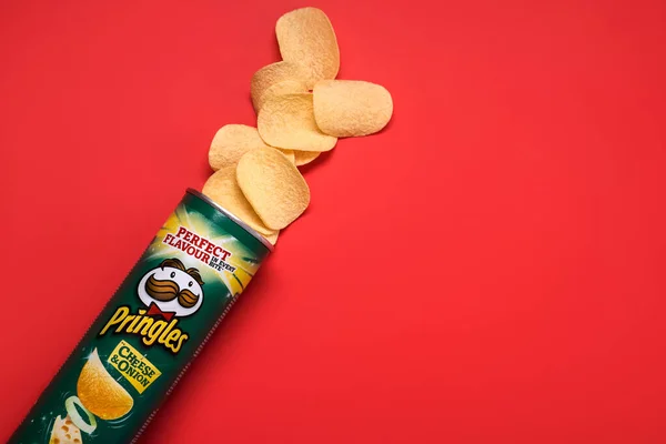 プリングルズチーズと玉ねぎ 赤の背景にプリングルズポテトチップスと段ボールチューブ缶 — ストック写真