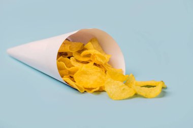 Mavi arka planda lezzetli patates cipsli kâğıt koni.
