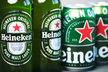 Heineken bira şişeleri ve Heineken bira kutuları yeşil arka planda.