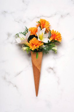 Mermer bir masada çiçekli dondurma külahı.