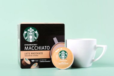 Starbucks latte Macchiato kahve kapsülleri beyaz kahve ve yeşil arka planda kapsül latte macchiato yanında.