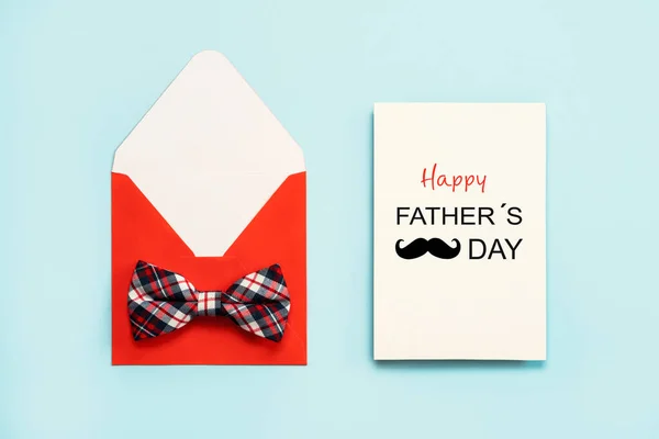 Happy Father\'s Day. Red envelope with bow tie and white paper with the text Happy Father\'s Day on a blue background