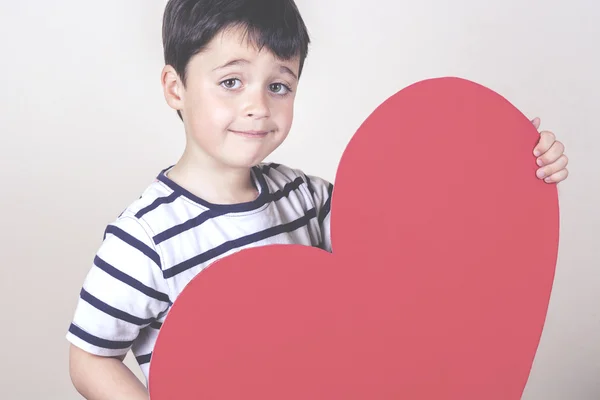 Menino sorridente com um coração vermelho para o Dia das Mães — Fotografia de Stock