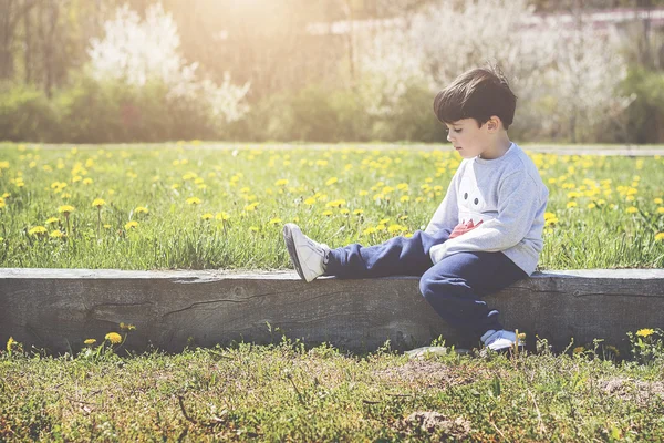 Nachdenklicher kleiner Junge sitzt auf Feld — Stockfoto