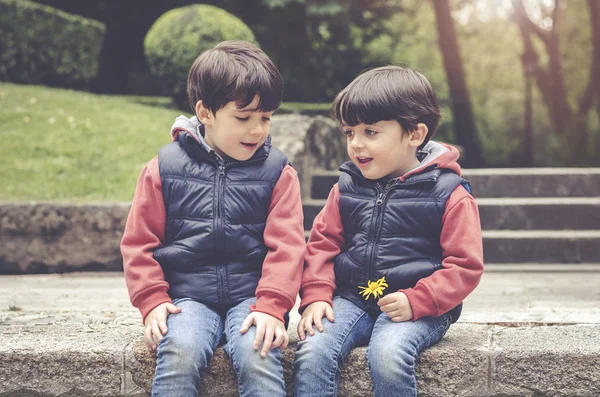 Irmãos felizes sentados no parque — Fotografia de Stock