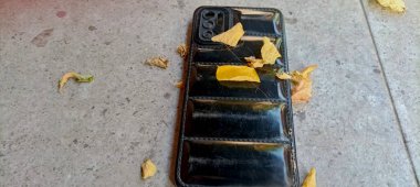 Yerde yapraklarla kaplı siyah plastik bir cep telefonu kılıfı vardı..