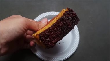 Beyaz bir tabağa çikolata serpiştirilmiş bir parça Pukis keki tutan bir el..