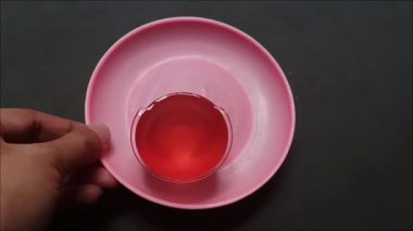 İçinde jöleli tatlı olan pembe bir tabağı tutan bir el..