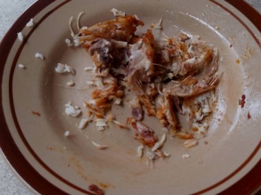 Yemekten sonra arta kalan kızarmış balık kemiklerinin ve dağınık pirinç tanelerinin yakın plan fotoğrafı..