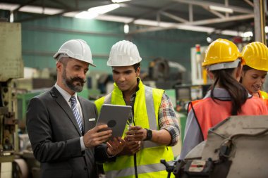 Erkek Endüstriyel Mühendisler Fabrika İşçisiyle konuşuyor. Ağır Sanayi Üretim Tesisinde çalışıyorlar..