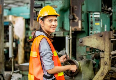 Fabrikada cnc makinası çalıştıran kadın mühendisler, elektronik kontrol panelindeki düğmelere basan gülümseyen işçilerin portresi ve modern fabrikada çalışan makine birimlerine bakarken kameraya bakan kadın mühendisler.