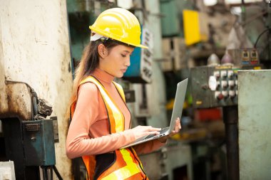 Üniformalı kadın teknisyen bilgisayarda makine üretiminde çalışıyor..