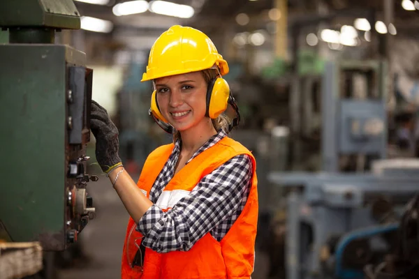 Elektronik kontrol panelinde düğmelere basan ve modern fabrikada çalışan makine birimlerine bakarken kameraya bakan gülümseyen işçilerin portresi, fabrikada bir cnc makinası çalıştıran kadın mühendisler