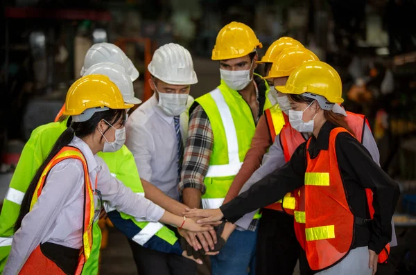 Group of Engineer manager and Factory Workers Team standing against production line.Male Industrial Engineers Talk with Factory Worker . They Work at the Heavy Industry Manufacturing Facility.