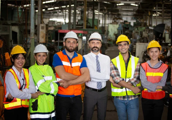 Group of Engineer manager and Factory Workers Team standing against production line..Male Industrial Engineers Talk with Factory Worker . They Work at the Heavy Industry Manufacturing Facility.