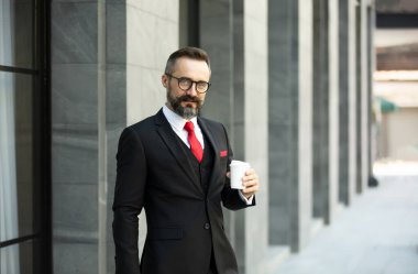 Sakallı hippi işadamı kahve fincanı portreleri tutuyor..