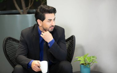 Elinde kahve fincanı tutan genç bir iş adamı. .