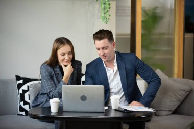 İki neşeli genç iş adamı iş görüşmesinde dizüstü bilgisayar kullanıyor.