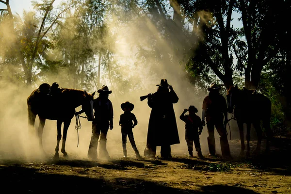 Cowboy Life: silhouette Group of Cowboy Caravan with lover horses standing with smoke.