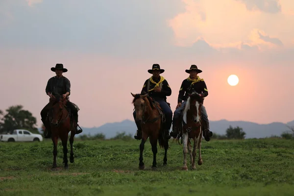 日没に向かって銃を持って騎乗するカウボーイ — ストック写真